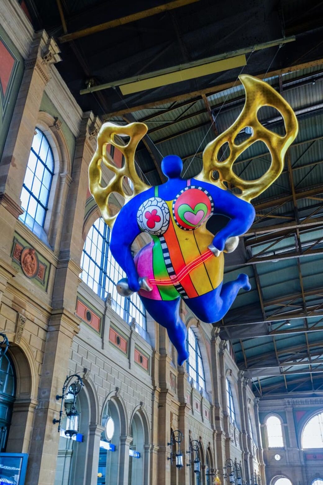 Public main concourse of Zürich Hauptbahnhof, beneath the suspended guardian angel; stop clear of passenger routes.