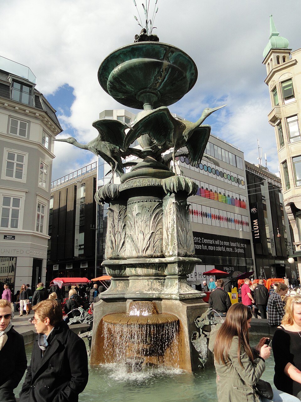 Public paving beside the Stork Fountain on Amagertorv, outside the basin and clear of the main pedestrian flow.
