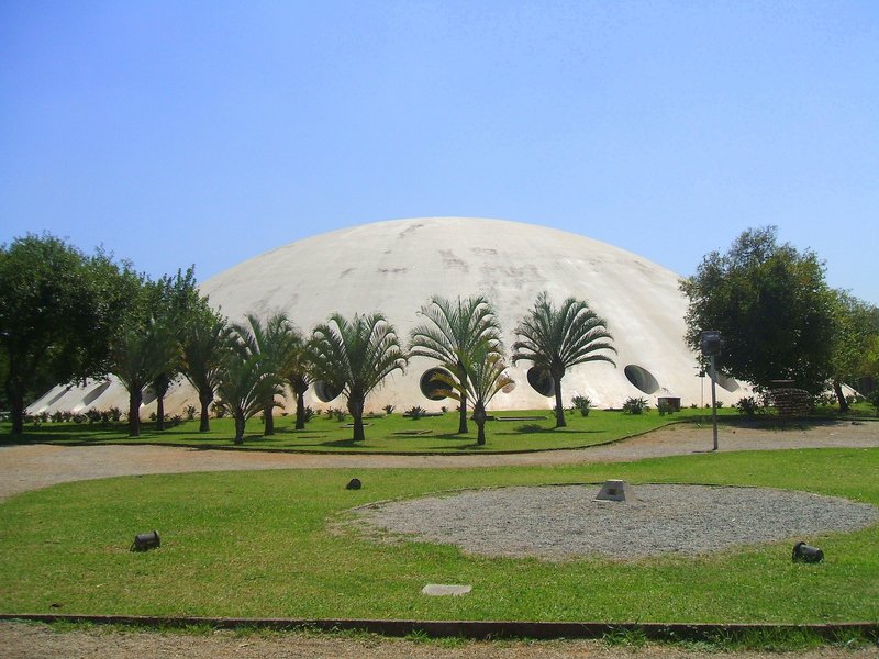 Open park path facing Oca’s white dome and circular openings, inside Parque Ibirapuera; stay outside the building.