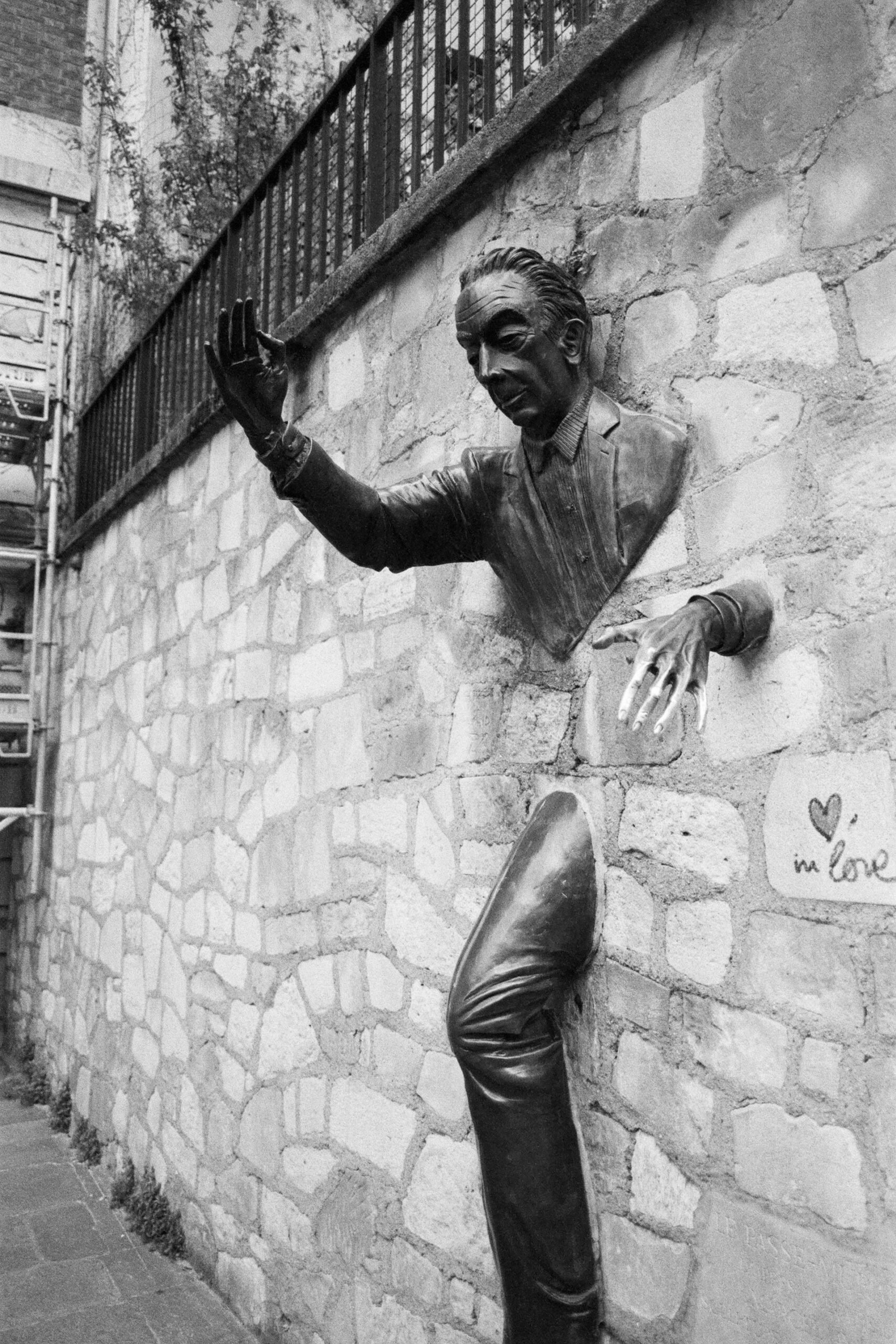 Public pedestrian space beside Le Passe-Muraille on place Marcel-Aymé, 75018 Paris. Keep a clear route beside the sculpture.