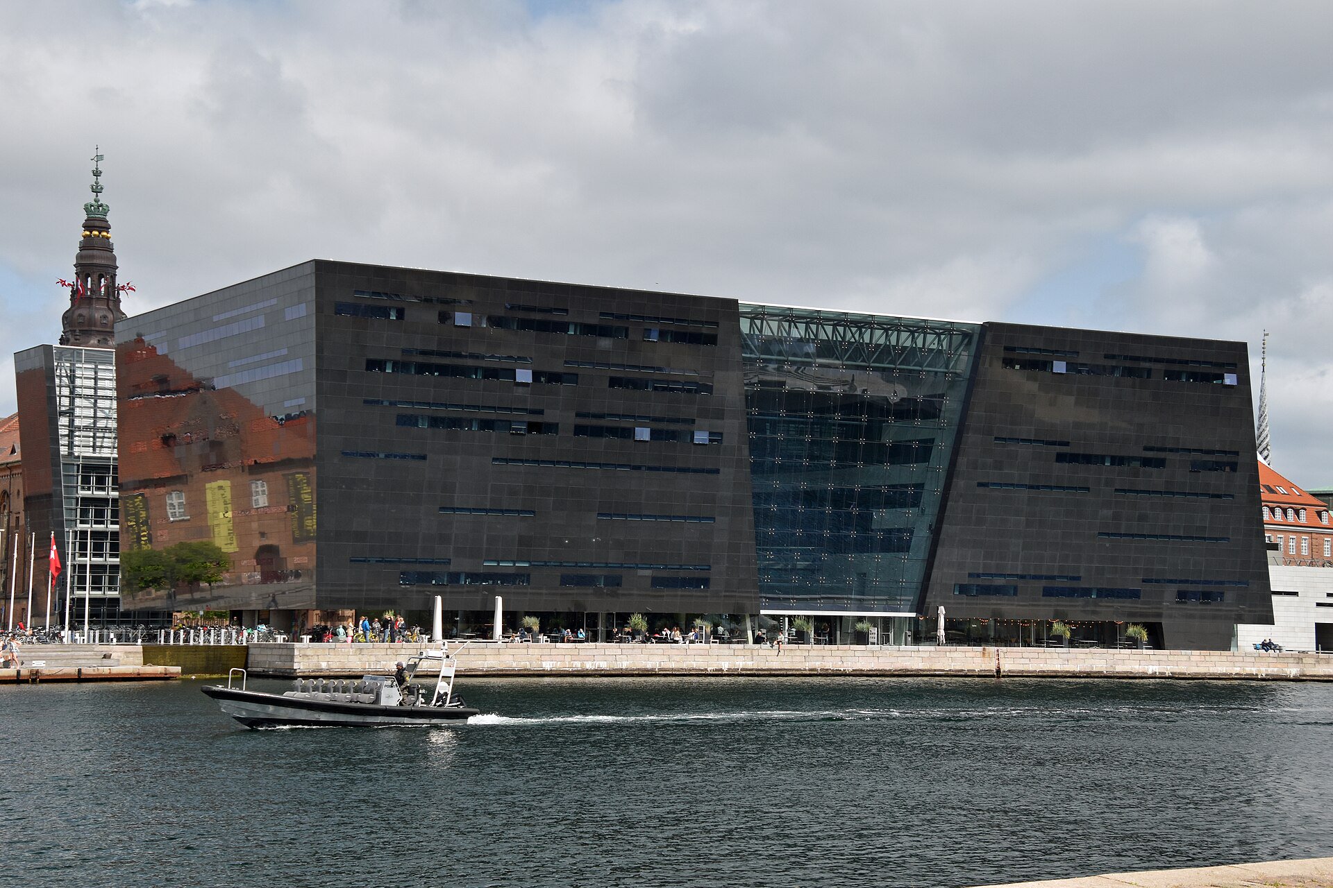 Public harbour promenade beside Den Sorte Diamant, Søren Kierkegaards Plads, set back from the water with a view of the black façade.