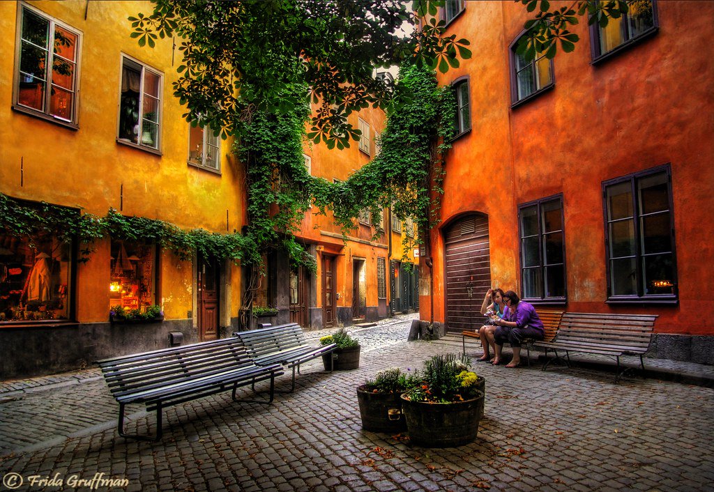 Public square at Brända Tomten, where Kindstugatan meets Själagårdsgatan. Stand beside the seating, leaving the narrow walking routes clear.