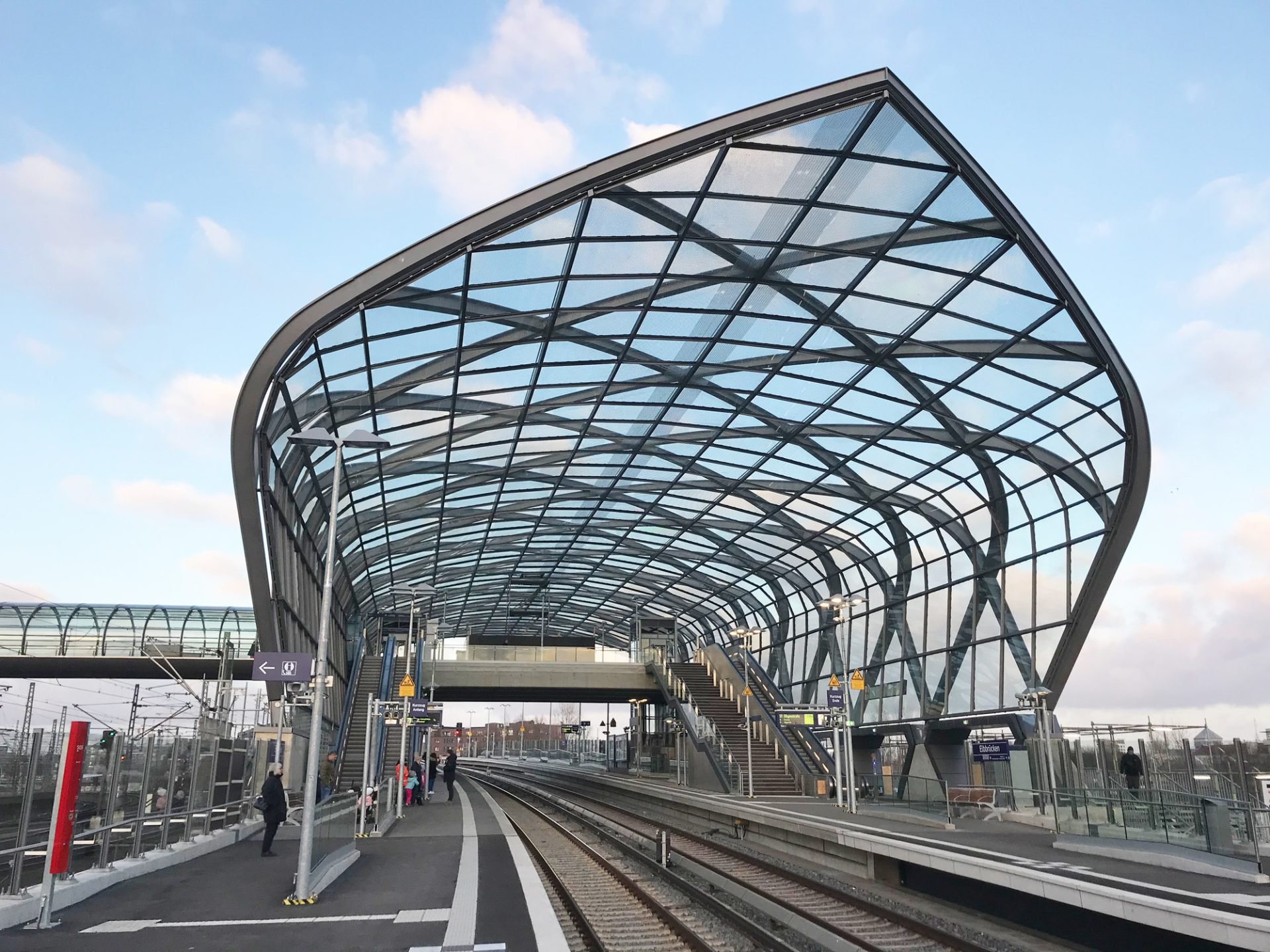 Public forecourt outside the U-Bahn Elbbrücken station, with a view of the curved steel-and-glass roof.