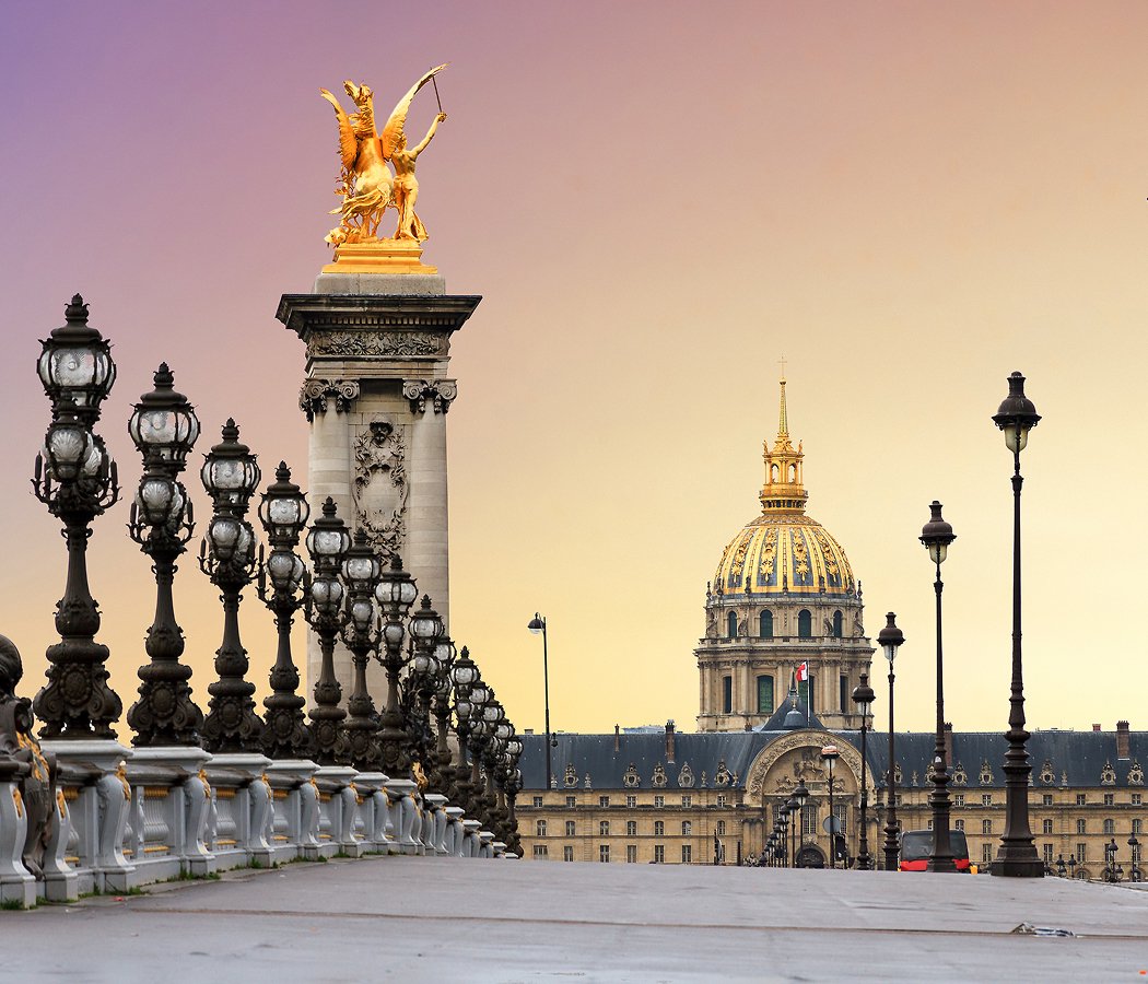 Wide public pavement beside a corner pylon of Pont Alexandre III, Paris. Stay away from the roadway and keep the crossing clear.