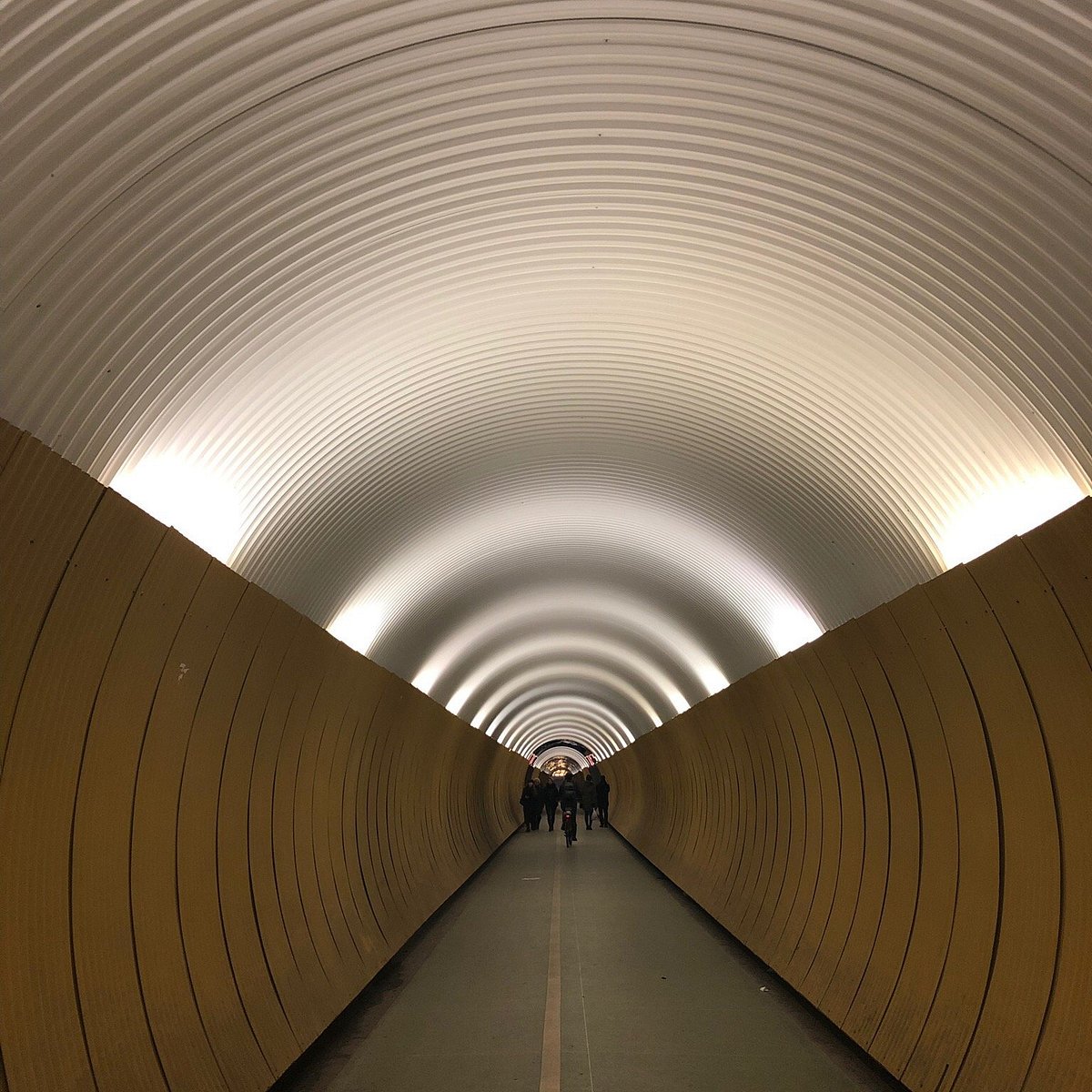 Public paving beside the E. H. Thörnberg statue at the western, Tunnelgatan entrance of Brunkebergstunneln. Keep the doorway clear; observe the tunnel from the entrance before walking through.