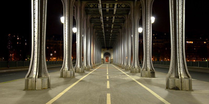 Designated pedestrian route beneath the Métro viaduct on Pont de Bir-Hakeim, Paris. Keep cycle routes and crossings clear.