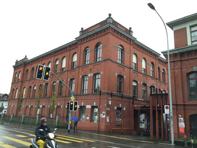 Open public exterior approach at Rote Fabrik, Seestrasse 395, facing the red-brick industrial buildings.